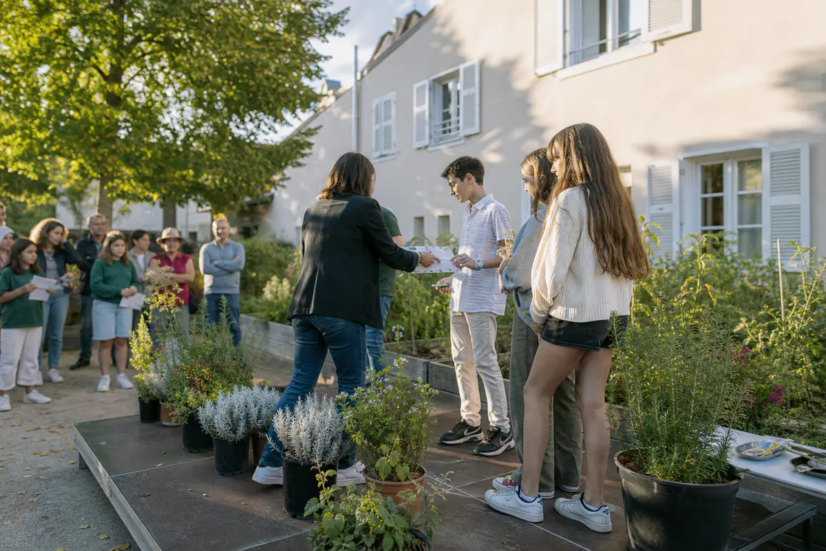 Élèves et jardiniers réunis devant des plantes en pots lors d’une cérémonie de remise de distinctions au collège
